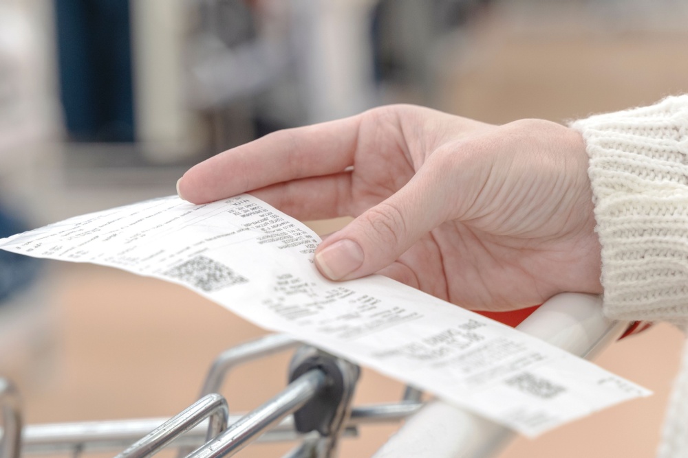 A woman looking at a receipt while shopping.