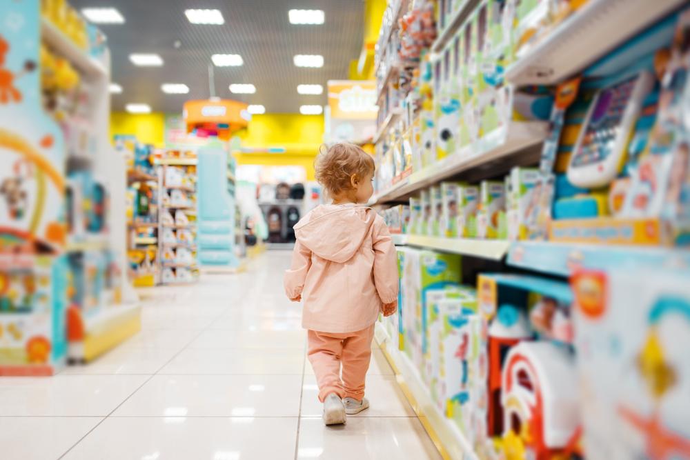 A child walking down the aisle of a toy shop.
